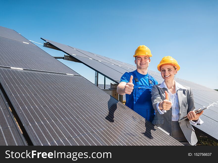 Worker and investor in solar power plant pointing at the sun