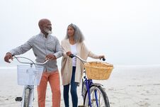 Couple Looking At Each Other While Holding Bicycles At The Beach Stock Images