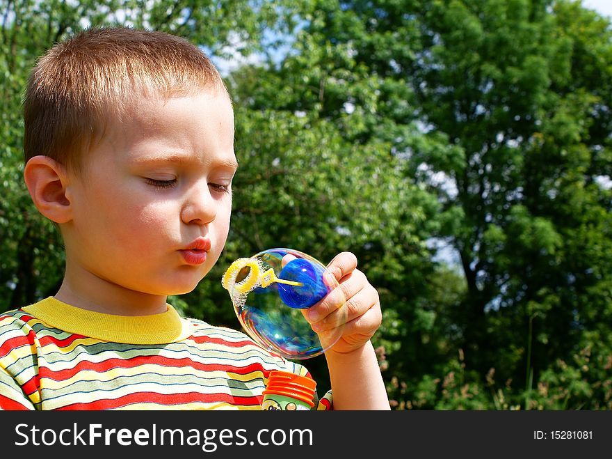 A child blowing bubble, background tree