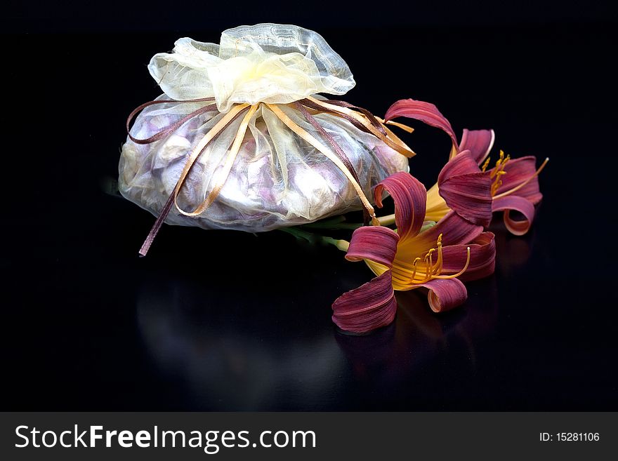 A bag of potpourri and lilies on a black background. A bag of potpourri and lilies on a black background.