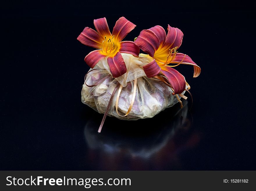 Red and yellow lilies on a bag of potpourri. Red and yellow lilies on a bag of potpourri.