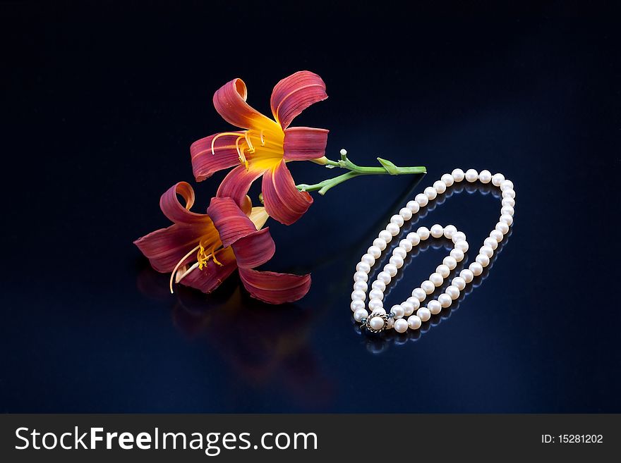 Red and yellow lilies and a pearl necklace.