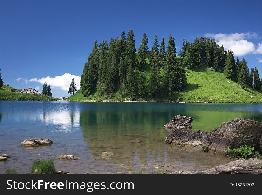 Swiss mountain landscape with a lake, forest and wooden house on shore