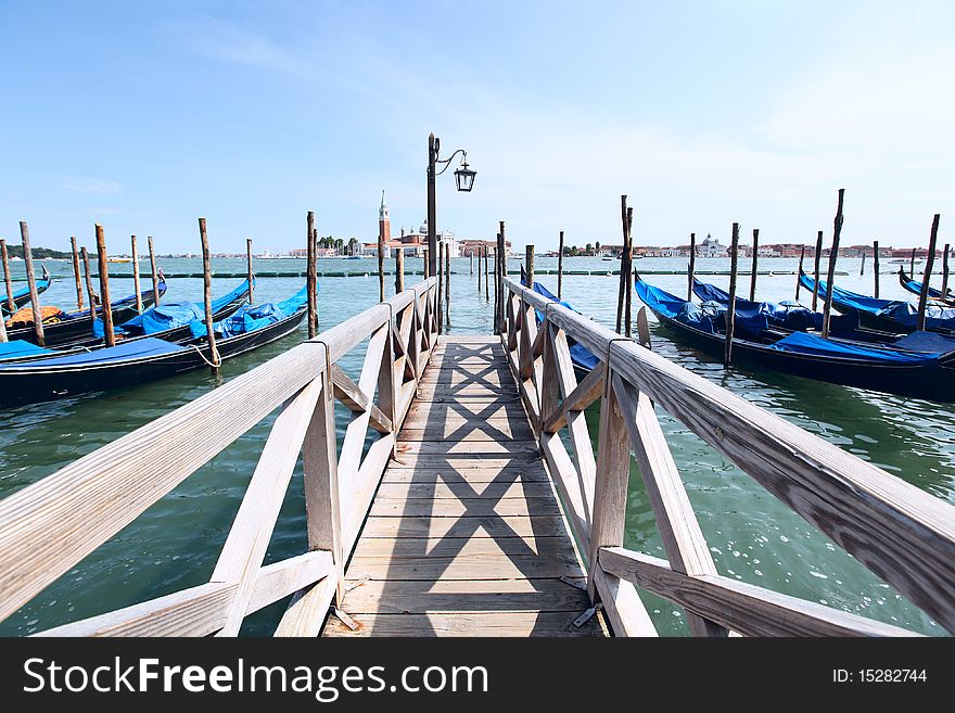 A row of gondola boats anchored along the Grand Canal in Venice, Italy. A row of gondola boats anchored along the Grand Canal in Venice, Italy.