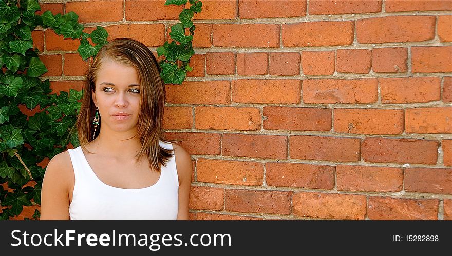 Attractive teen posing against a brick wall on a warm summer day.