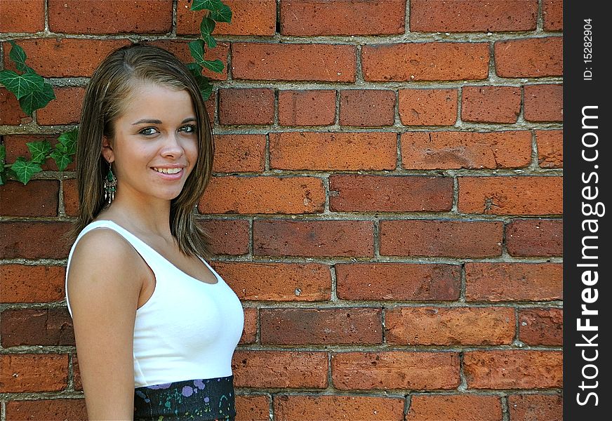 Attractive teen posing against a brick wall on a warm summer day.