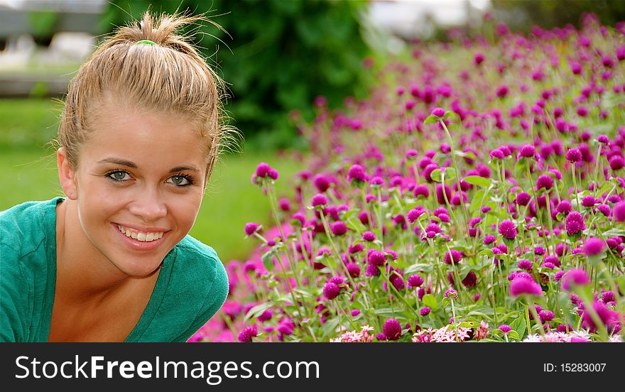 Beautiful teen girl relaxing by a garden of purple flowers on a warm summer day.