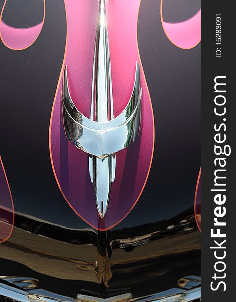 Detail of chrome hood ornament with pink flames. Detail of chrome hood ornament with pink flames