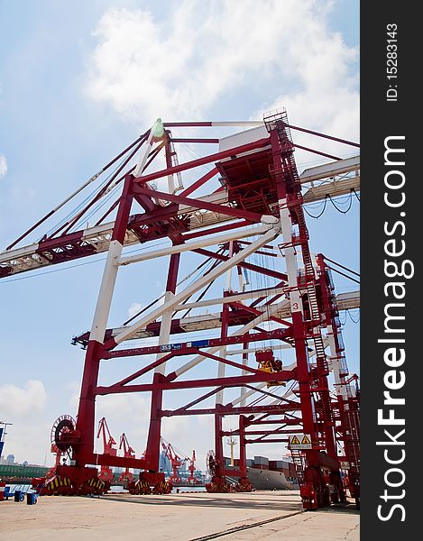 Rows of shipping containers, with a large crane overhead, lifting more containers into place. Rows of shipping containers, with a large crane overhead, lifting more containers into place