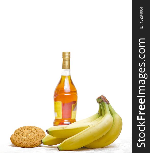 Bottle of  brandy, yellow banana and cookie isolated. Bottle of  brandy, yellow banana and cookie isolated