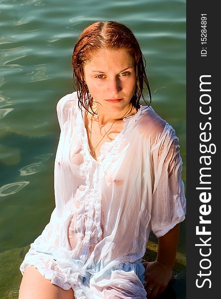 The girl in a wet white shirt on coast of lake. The girl in a wet white shirt on coast of lake
