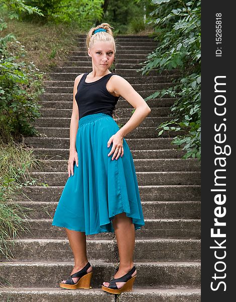 Beautiful young lady standing on old staircase somewhere in green park. Beautiful young lady standing on old staircase somewhere in green park