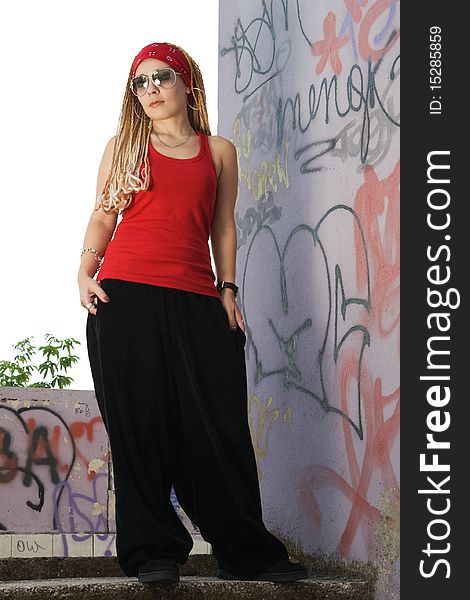 Teenage rapper girl standing outdoors at graffiti sprayed wall. Teenage rapper girl standing outdoors at graffiti sprayed wall