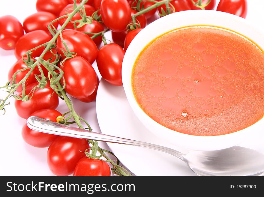Tomato soup with fresh tomatoes around it and a spoon