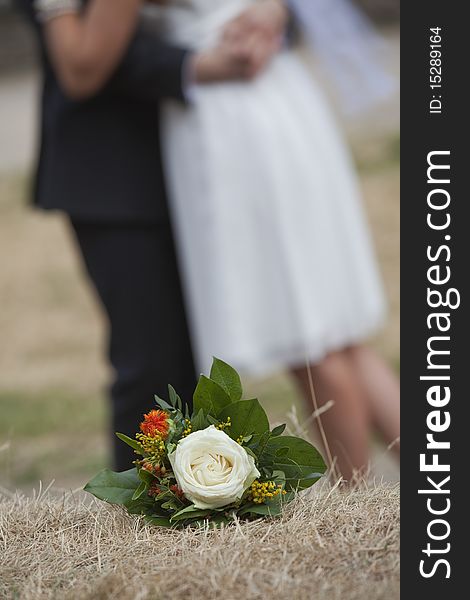 Wedding bouquet with rose on the ground - wedding couple in background