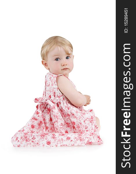 Beautiful little girl sits in flowered dress on white background.