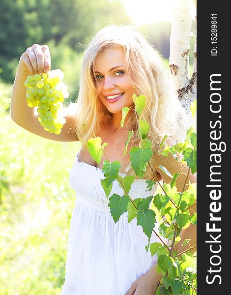 Beautiful girl holding grapes on a light background