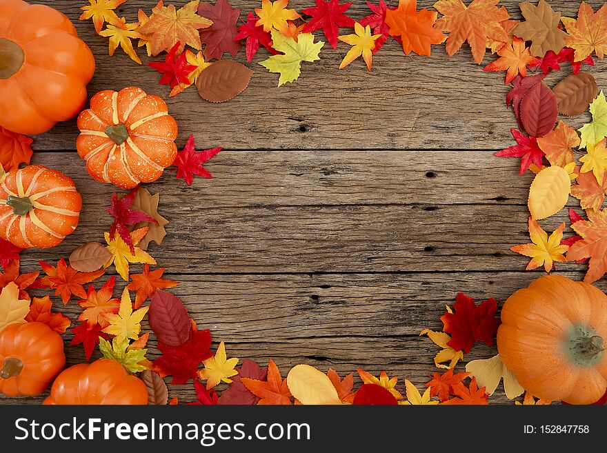 Autumn multicolored  leaves and pumpkins old brown wood table background with copy space, flat lay, minimal concept. Autumn multicolored  leaves and pumpkins old brown wood table background with copy space, flat lay, minimal concept