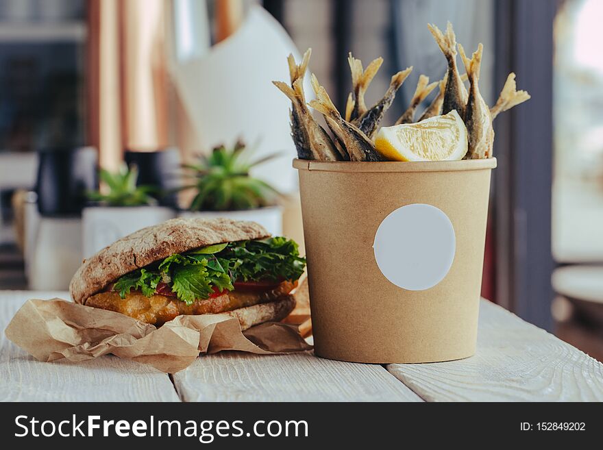 Grilled sea fish with lemon wedges street food in box on wooden background