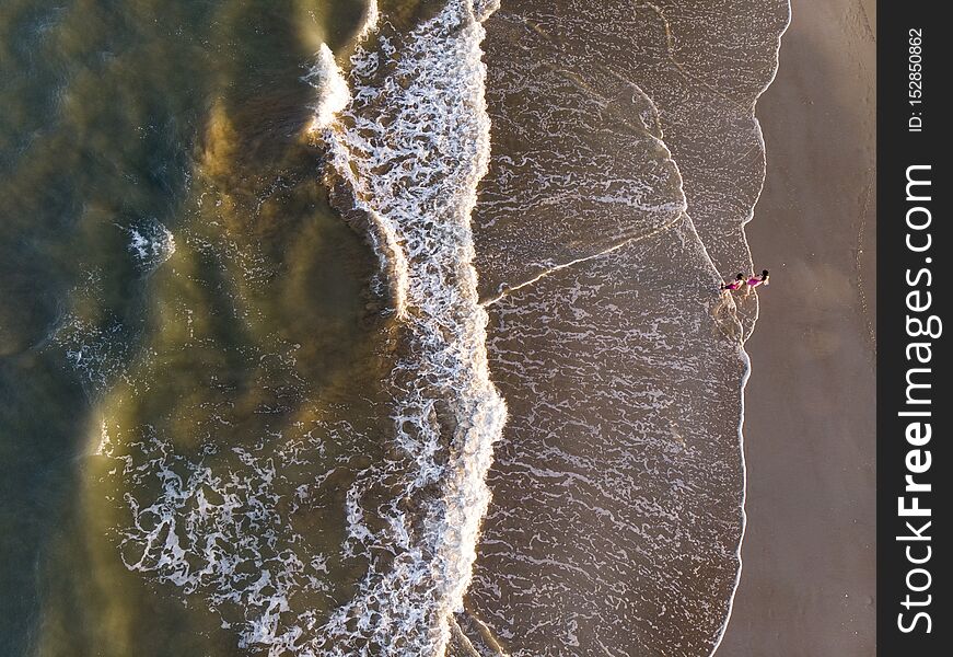 Aerial landscape  made with a drone of two girls walking in the beach. Aerial landscape  made with a drone of two girls walking in the beach.