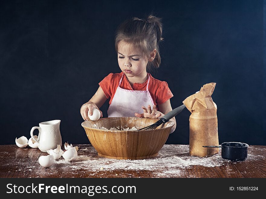 A litlte girl cracks open an egg into a bowl in the kitchen. A litlte girl cracks open an egg into a bowl in the kitchen