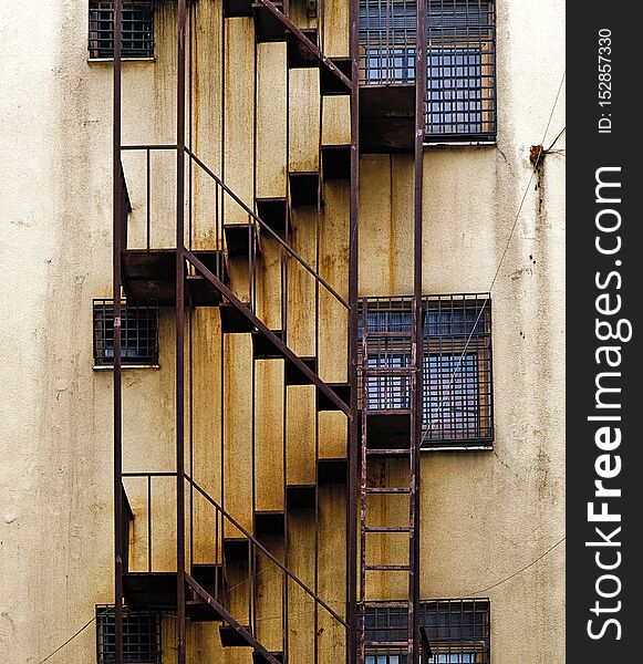 Urban building  back alley fire escape rusty stairs on aged wall. Urban building  back alley fire escape rusty stairs on aged wall