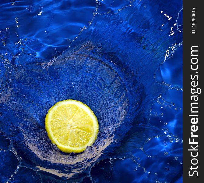 Half of lemon splashing blue water