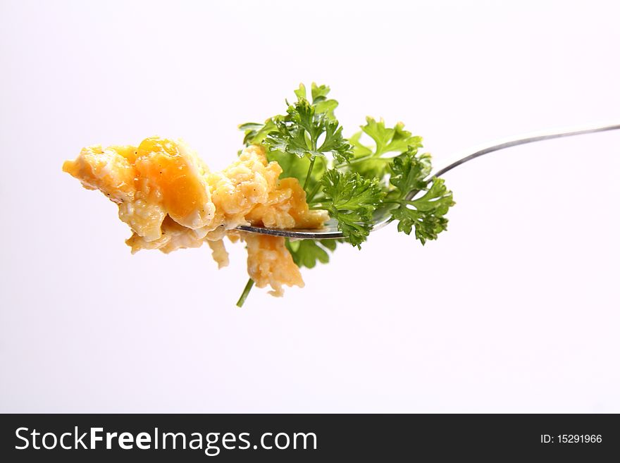 Scrambled eggs on a fork, decorated with parsley