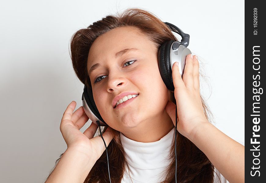 Beautiful girl with headphones on a light background