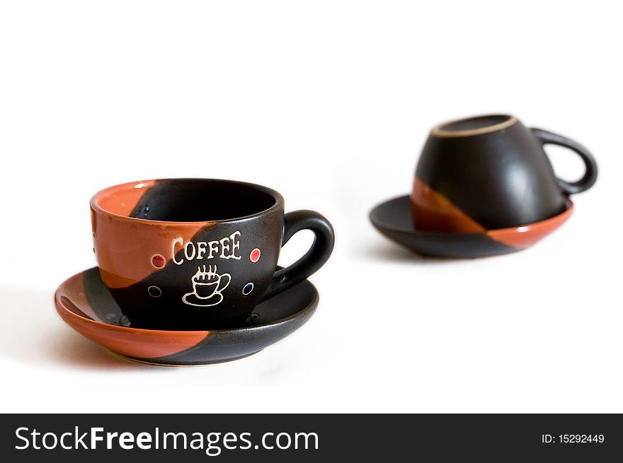 Two empty cups for coffee stand on a saucer. Separately from a background. One is turned.