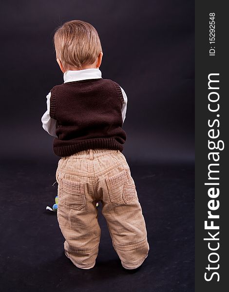 Cute little boy from behind over black background