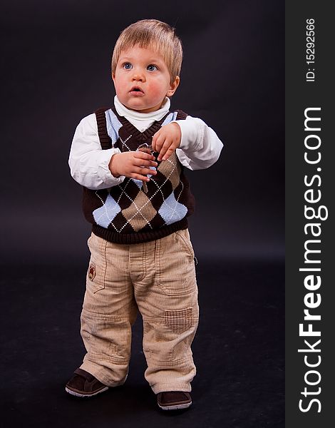 Cute little boy with keys over black background