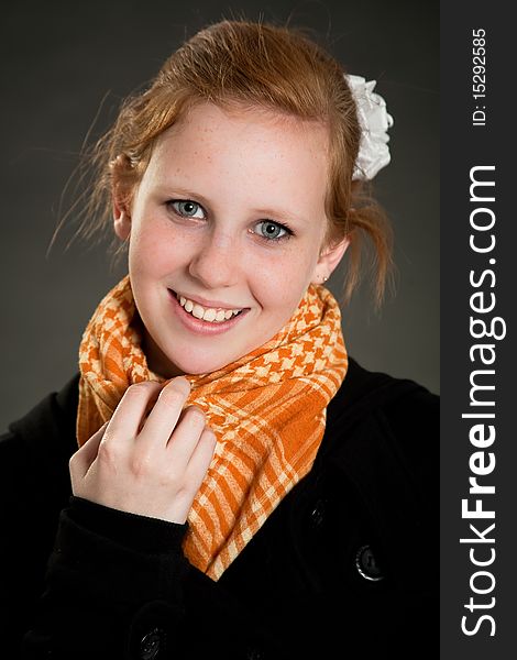 Beautiful teen girl with scarf in front of dark green background