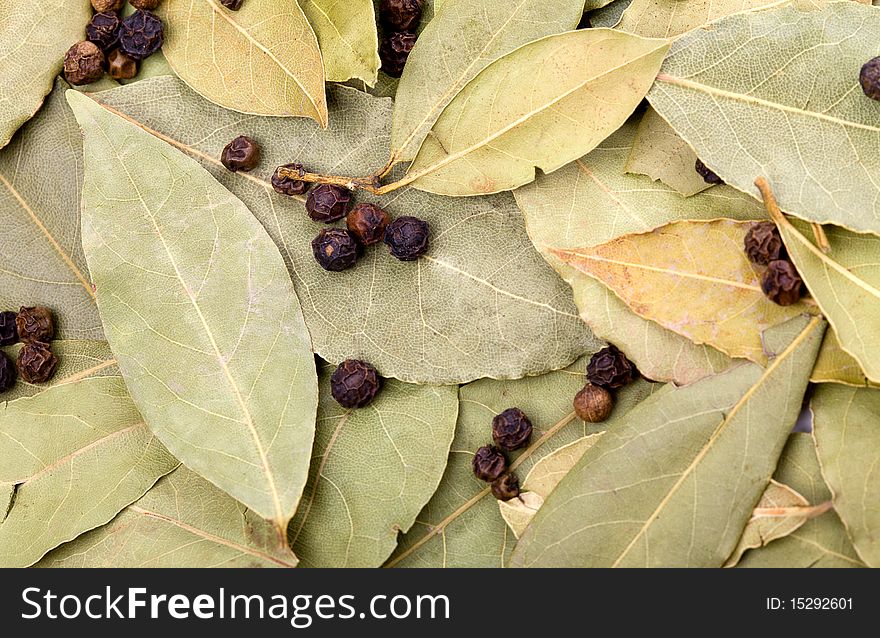 Background of bay leaves and black peppercorns
