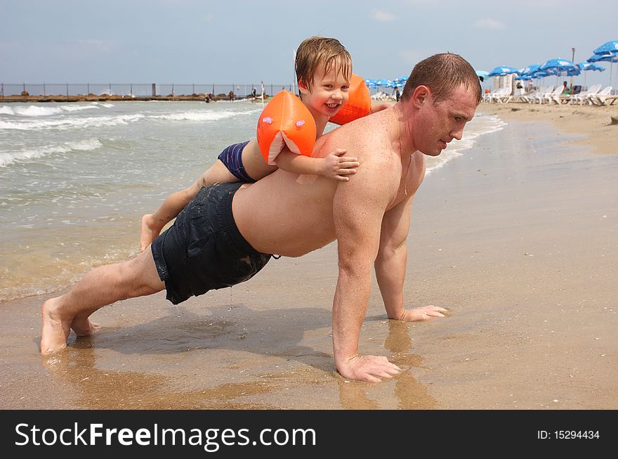 Father is in the fitness on the beach with his son. Father is in the fitness on the beach with his son