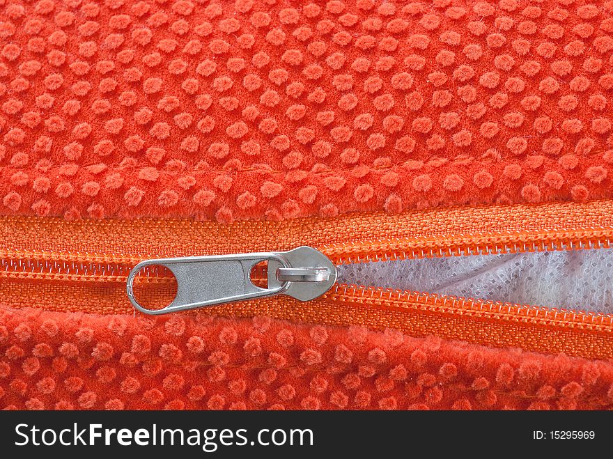 Studio shot of orange zipper, halfway open.