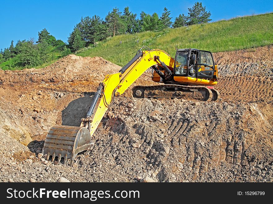 Excavator loading truck shot against the background of the pit and blue sky. Excavator loading truck shot against the background of the pit and blue sky