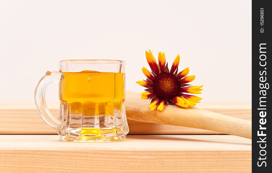 Honey in a small mug on wood with a wooden spoon and flower. Honey in a small mug on wood with a wooden spoon and flower