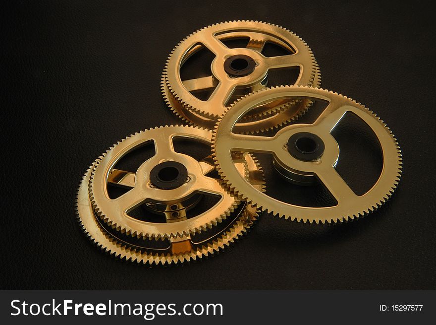 Three gold colored gear wheels, two pushing the other to one side. Three gold colored gear wheels, two pushing the other to one side.