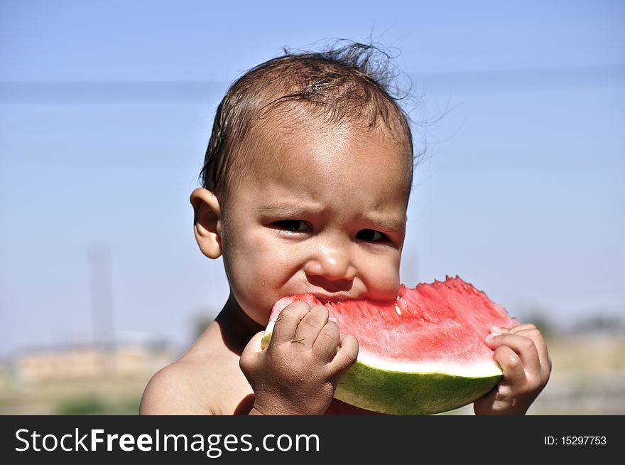 Child eating watermelon and looks into the camera. Child eating watermelon and looks into the camera