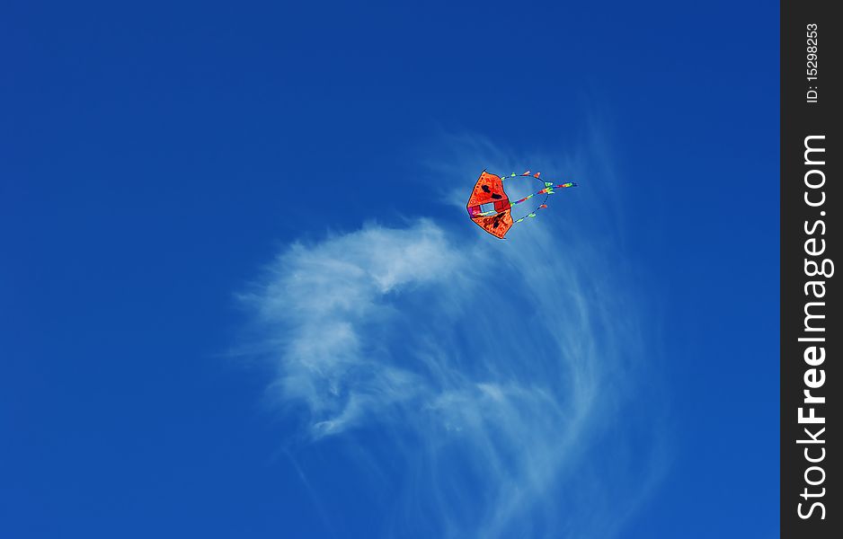 A kite flies in the bright blue sky. A kite flies in the bright blue sky