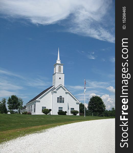 A beautiful white church sits on a hillside against the bright blue of the sky. A beautiful white church sits on a hillside against the bright blue of the sky.