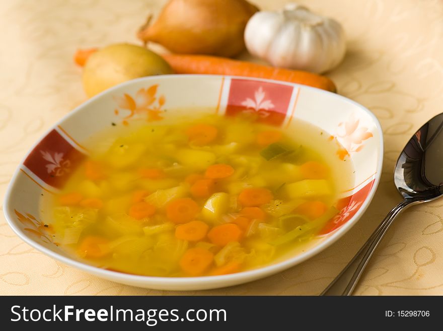 Clear soup with mixed vegetable , carrot , potato , parsley , onion