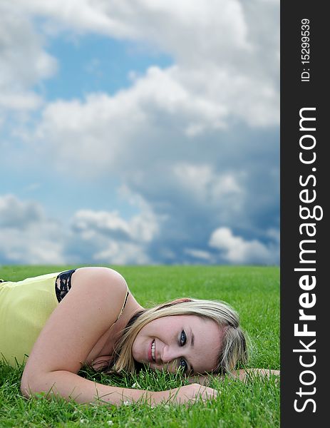 Closeup of a beautiful blond white Caucasian young adult teenage girl laying in a green grass field smiling at the camera. Closeup of a beautiful blond white Caucasian young adult teenage girl laying in a green grass field smiling at the camera.