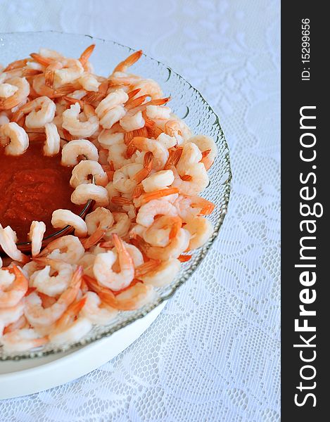 A bunch of shrimp arranged in a bowl with red sweet sauce for dip. A bunch of shrimp arranged in a bowl with red sweet sauce for dip.