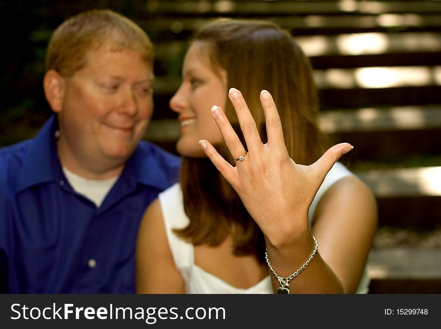 A couple in love series shot in the woods. The engaged young woman is proudly showing off her engagement ring. A couple in love series shot in the woods. The engaged young woman is proudly showing off her engagement ring.