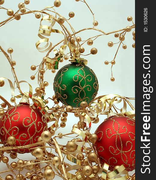 A trio of red and green Christmas ornaments decorated with ribbons and gold berries. A trio of red and green Christmas ornaments decorated with ribbons and gold berries