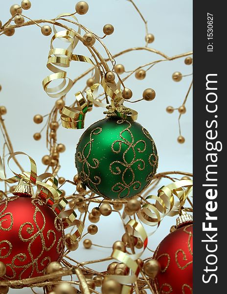 A trio of red and green Christmas ornaments decorated with ribbons and gold berries. A trio of red and green Christmas ornaments decorated with ribbons and gold berries