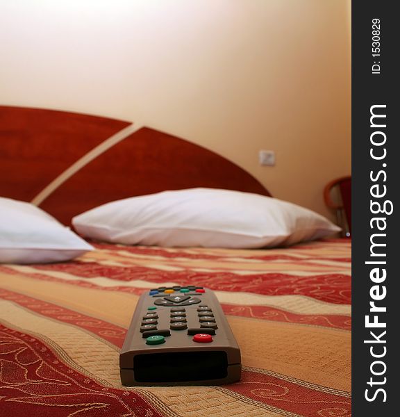 Luxury hotel room decor accommodation with TV remote in front plane, selective focus on remote