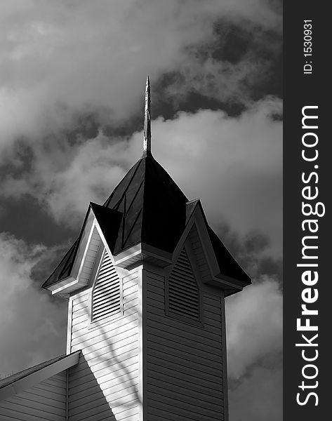 Old wooden church cupola or steeple with clouds in the sky in black and white. Old wooden church cupola or steeple with clouds in the sky in black and white